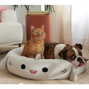 Dog resting inside a soft grey shark-shaped bed